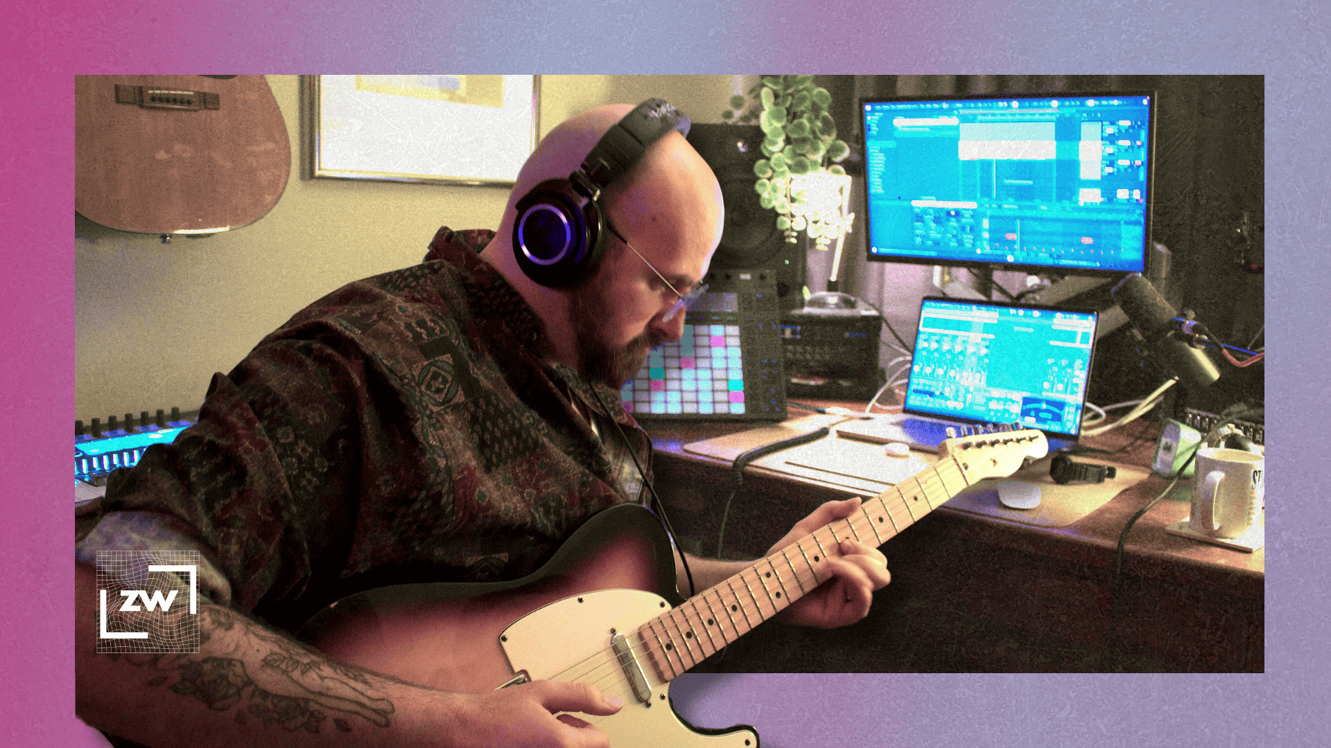 Image of me sitting at my desk playing guitar against a pink background